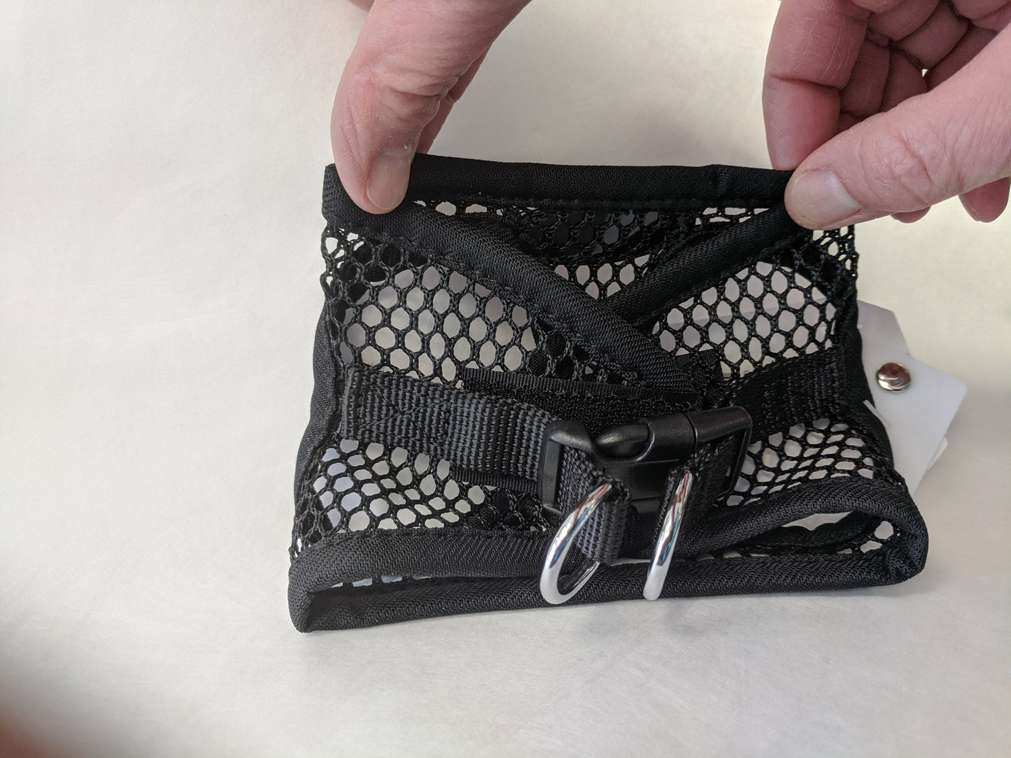 The XX Small EZ Wrap harness in black net held to show the tiny size.